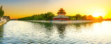 View of the Forbidden City with the reflection on the moat at sunset in Beijing, China.