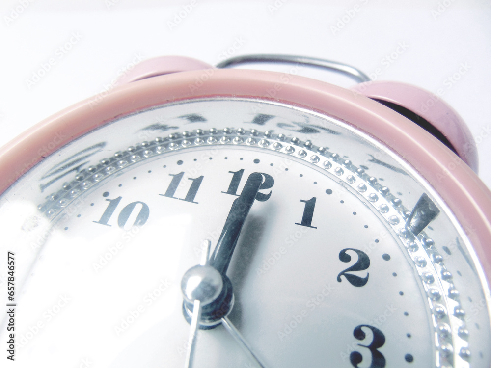 The old pink alarm clock showed one minute past twelve. isolated on white background close up view from above. The old pink alarm clock showed one minute past twelve. isolated on white background close up view from above.