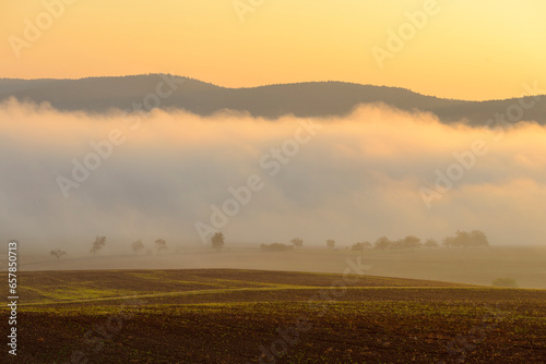 Countryside with morning mist over fields illuminated by the sun at Grossheubach in Bavaria, Germany