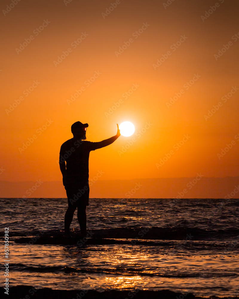 Silhouette of a man holding the sun