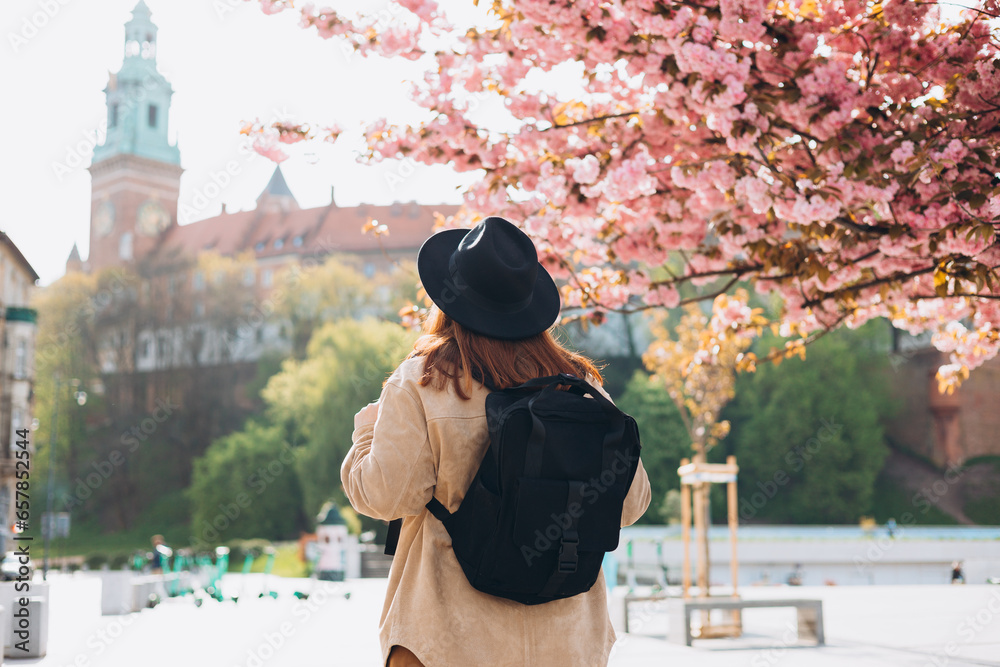 Attractive young female tourist is exploring new city. Redhead 30s girl resting in Krakow. Traveling Europe in spring, no face. High quality photo