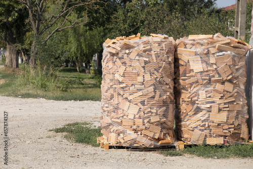 Firewood in a net for sale, big pile of firewood on pallet at the depot