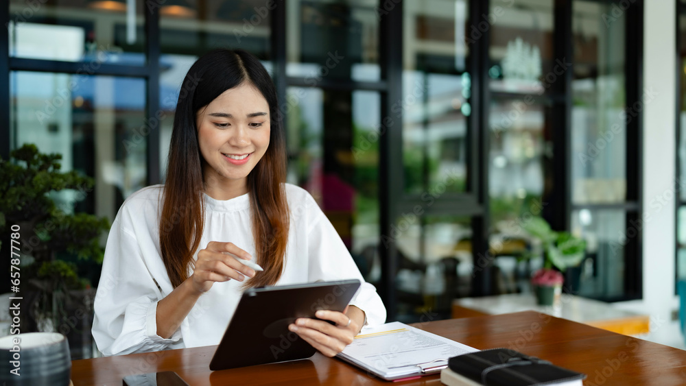 Fototapeta premium Writer woman is thinking creative ideas and writing business information content on tablet in cafe..