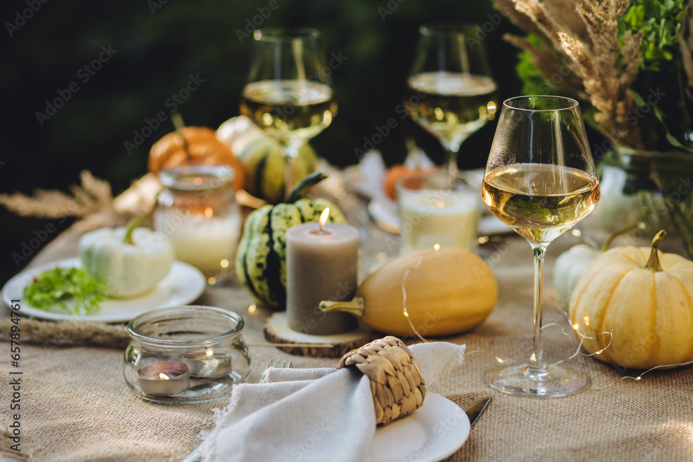 Fall still-life. Orange pumpkins, dry flowers and candles on linen tablecloth. Dinner table outdoors in the garden. Cozy autumn concept., simple handmade decoration, countryside style