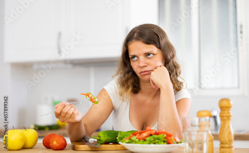 Portrait of disappointed young woman cooking at home kitchen