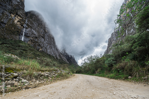 Scenery of a path between rocky mountains, with a waterfall and vegetation. Travel concept photo