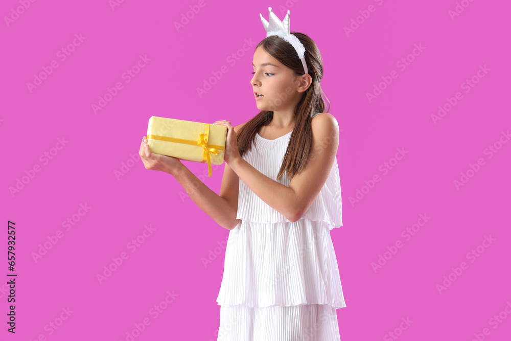 Surprised little girl with Birthday gift box on purple background Surprised little girl with Birthday gift box on purple background