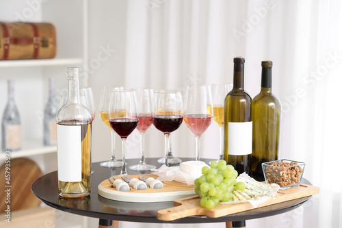 Glasses and bottles of wine with snacks on table in kitchen