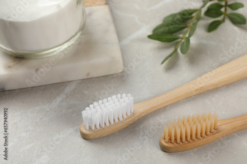 Bamboo toothbrushes and jar of baking soda on light grey marble table  closeup