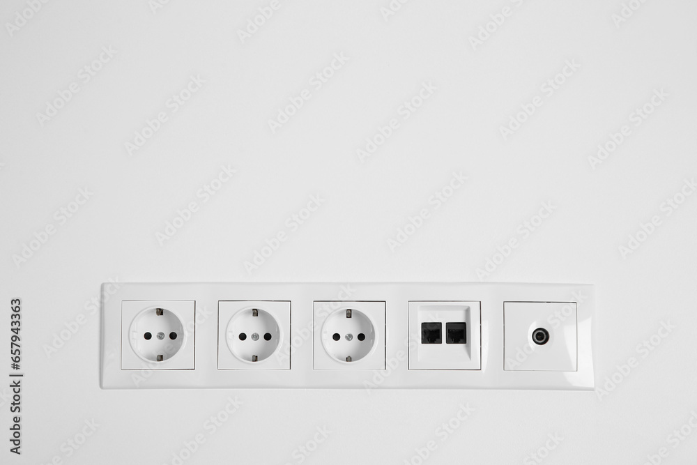 Many power sockets with ethernet and TV coax plates on white wall indoors. Space for text Many power sockets with ethernet and TV coax plates on white wall indoors. Space for text