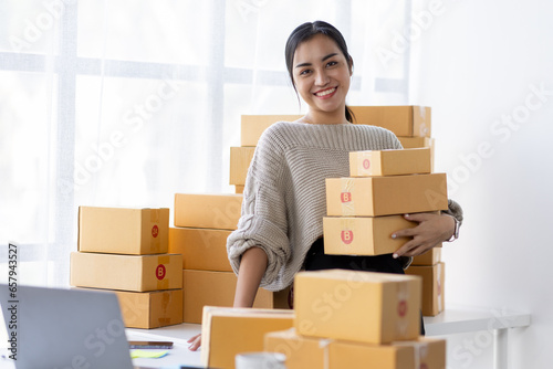 businesswoman start small business and successful SME entrepreneurs asian woman hoding boxs works from home delivering parcels online. SME delivery concept and packaging © David