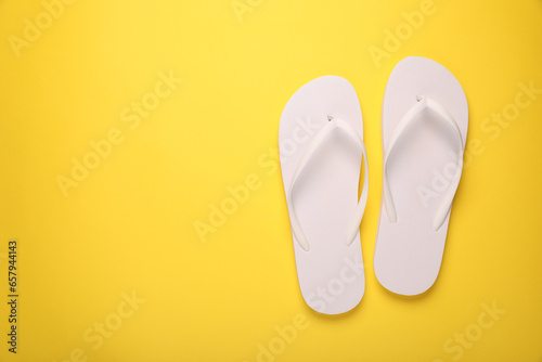 Stylish flip flops on yellow background, top view. Space for text