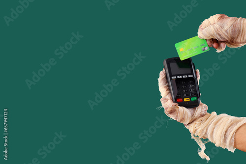 Fotobehang Mummy hands with credit card and payment terminal on green background
