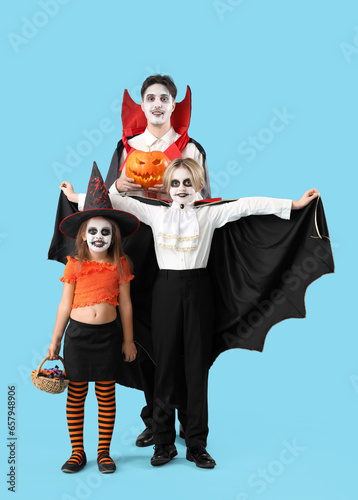 Happy family dressed for Halloween on blue background