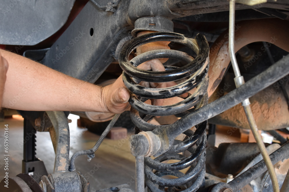 Male Hand on Spring while Working on Suspension of Vehicle Male Hand on Spring while Working on Suspension of Vehicle