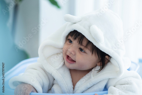 Cute baby girl wearing a bathrobe  good feeling after bathing, looking and smiling at someone