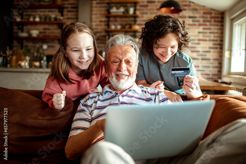 Wallpaper Mural Grandfather and grandchildren online shopping from a laptop on the couch at home Torontodigital.ca