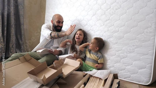 Wallpaper Mural Dad with kids are on the floor reading paper instruction for a new bed in the kids bedroom. Interior structure of furniture. Helping father mounting furniture. Family activity together. Torontodigital.ca