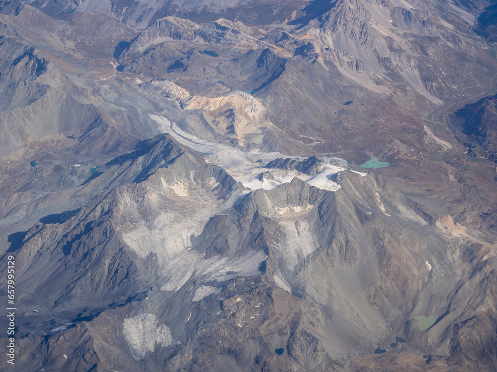 Flying over the European Alps during fall season. Landscape at the glaciers. Melting of glaciers due to global warming. Aerial view from the airplane window