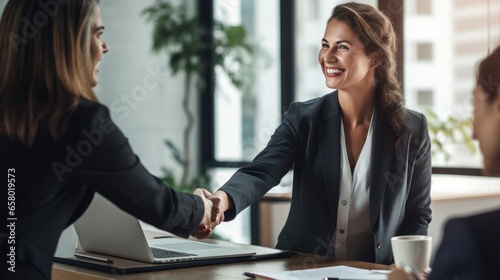 Happy business woman manager handshaking client for successful deal at meeting table in office.