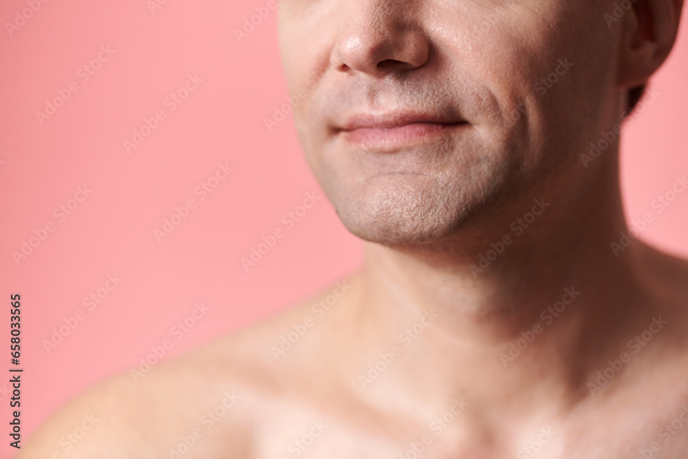 Cropped image of smiling shaved mature man standing against pink background Cropped image of smiling shaved mature man standing against pink background