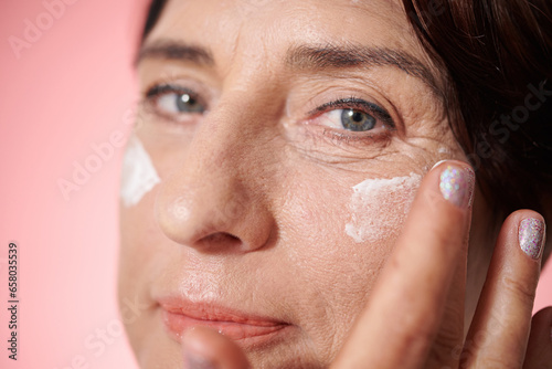 Mature woman applying nourishing moisturizing face mask at night