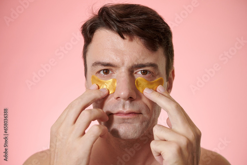 Portrait of mature man applying hydrogel patches to reduce fine lines photo