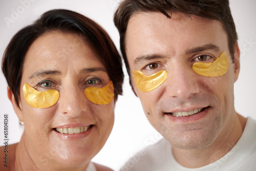 Faces of smiling mature man and woman wearing hydrogel patches, skincare and beauty concept photo