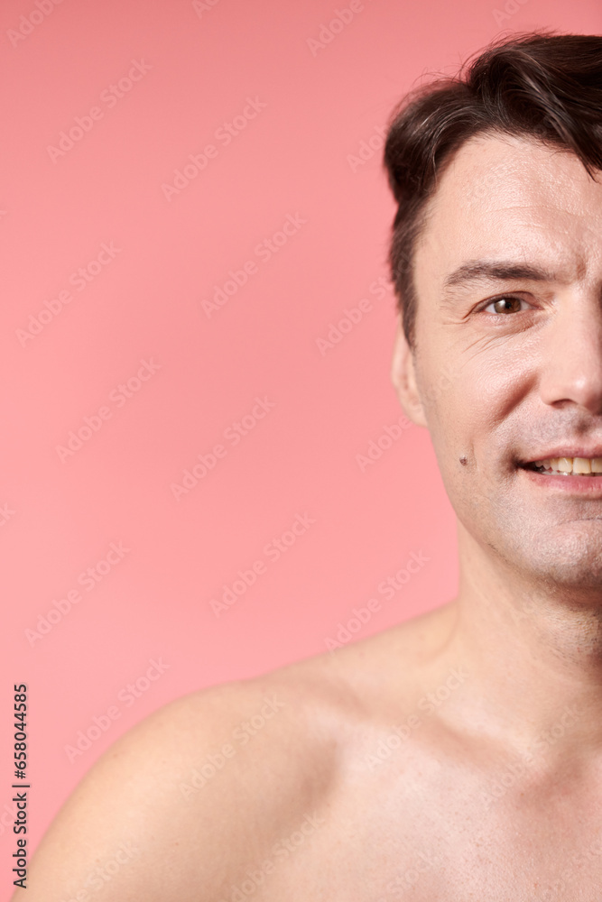 Portrait of positive shirtless mature man standing against pink background