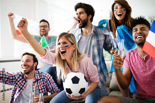 Cheerful and happy group of friends watching olympic games on tv.