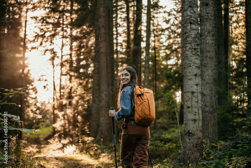 Latina woman embarking on a solo hiking adventure through the enchanting beauty of a mountain forest, fully prepared with hiking gear