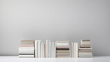 A stack of books on a white wall. This image shows a pile of books of different sizes and colors stacked in a random manner on a white background. The books are mostly white or light-colored, creating