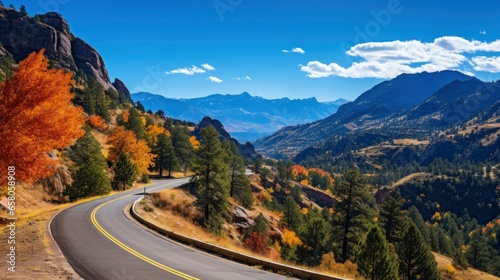 Autumn mountain road. The scene unfolds against a backdrop of tree-covered peaks, their leaves creating an unforgettable contrast against the deep blue sky.