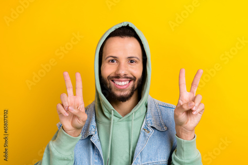 Photo of funky positive person beaming smile hands fingers demonstrate v-sign isolated on yellow color background