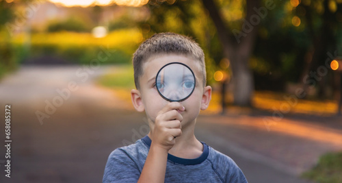 boy looks into a magnifying glass. Selective focus