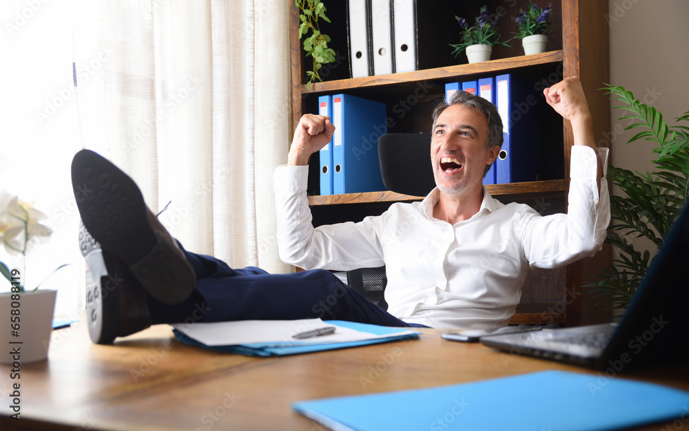 © Davizro Photography - Euphoric businessman celebrating work success with feet on the table © Davizro Photography - Euphoric businessman celebrating work success with feet on the table
