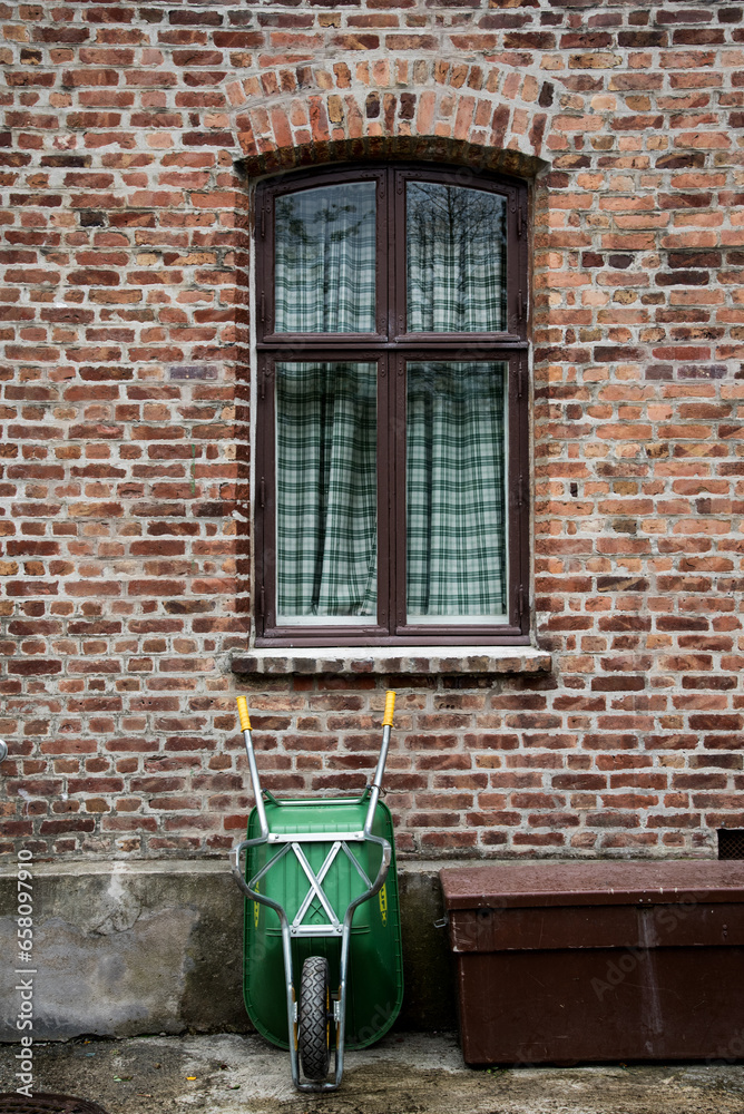 Naklejka premium wheelbarrow near the old brick wall 
