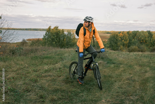  active lifestyle.A cyclist with a backpack in a protective helmet rides through the autumn forest and looks away
