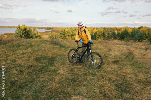 active lifestyle.A cyclist with a backpack in a protective helmet stands in the autumn forest and looks away