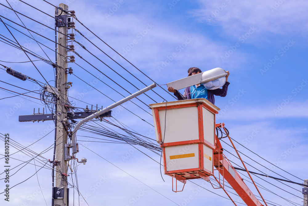 Electrician in bucket boom truck is repairing street light pole against