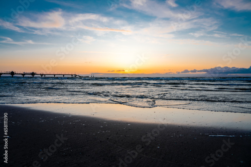 Pier on the beach near Misdroy in Poland. Natural coastal section on the Polish Baltic Sea. Landscape by the sea with sunset at the pier.