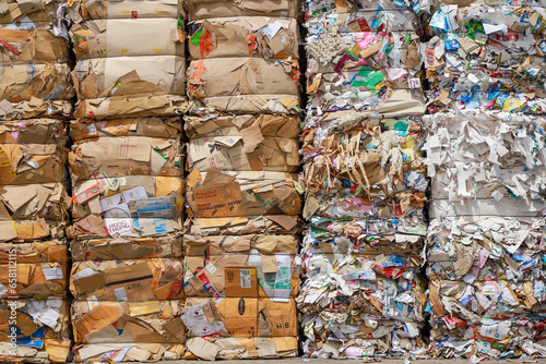 Bales of cardboard and box board with strapping wire ties before shredding at recycling plant
