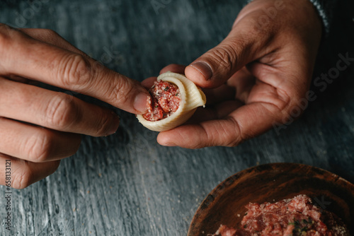 man filling a Catalan galet with raw ground meat photo