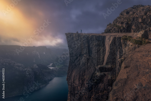 The first rays of sunrise at Preikestolen. A couple of tourists on Preikestolen (Pulpit Rock) enjoy the first rays of sunrise. Preikestolen, Pulpit Rock, Rogaland, Norway photo