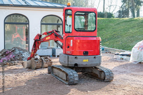Small red excavator. Construction excavator in a construction site.