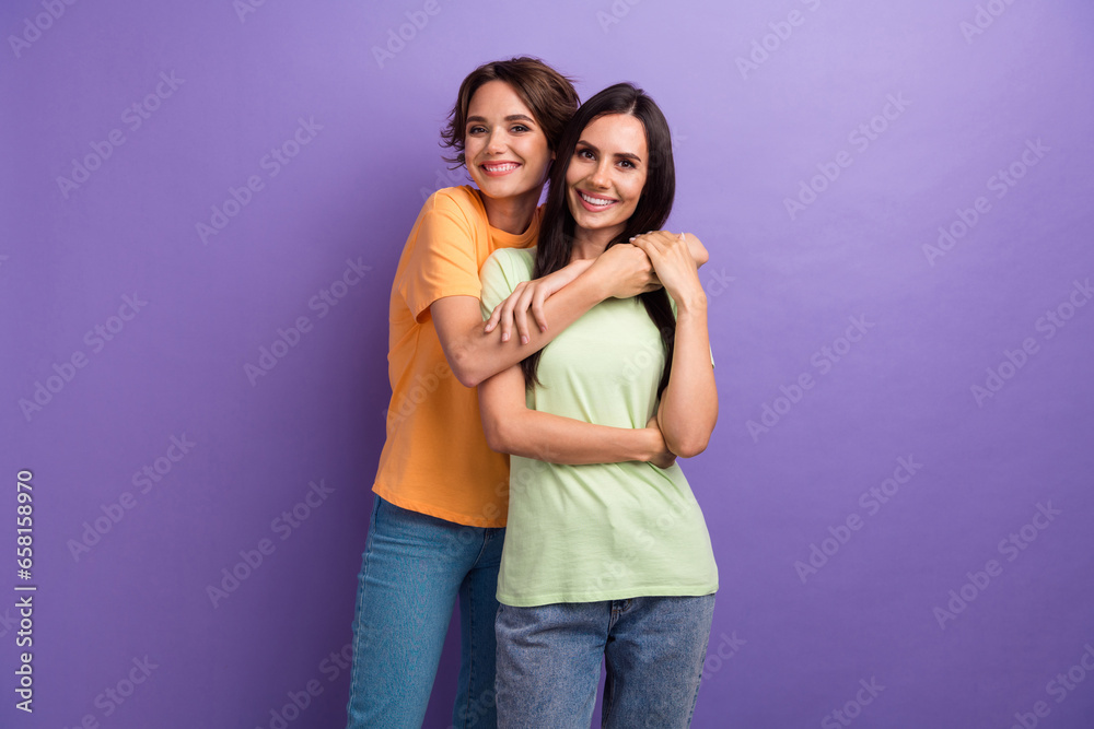 Photo of funky cheerful girls dressed t-shirts embracing smiling isolated purple color background Photo of funky cheerful girls dressed t-shirts embracing smiling isolated purple color background