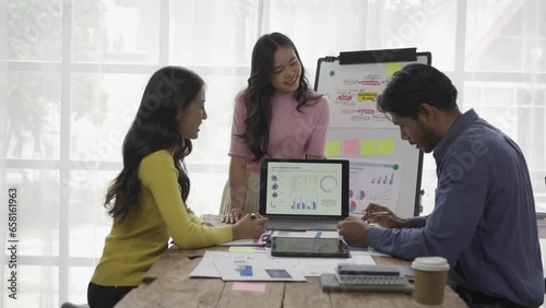 Group of Asian businessmen working in a meeting about business plans and presenting and explaining financial charts from laptops in business conference room with people sharing financial documents.