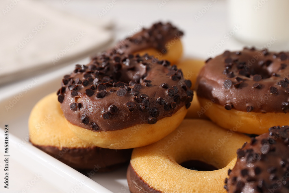 Chocolate donuts on plate on light background, close up Chocolate donuts on plate on light background, close up