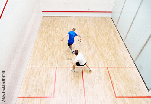 Schilderij op canvas Top view of two young men, friends, sportsmen playing squash on squash court