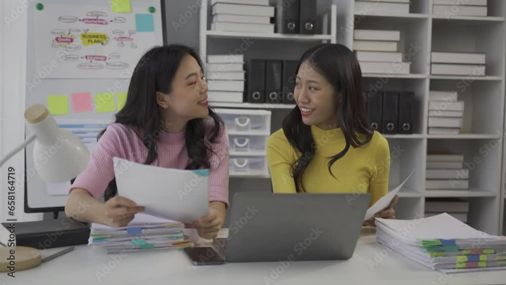 Two Asian business colleagues working together on a new project, businesswomen talking about finances, looking at patterns of markets, economies and banks. Two Asian business colleagues working together on a new project, businesswomen talking about finances, looking at patterns of markets, economies and banks.